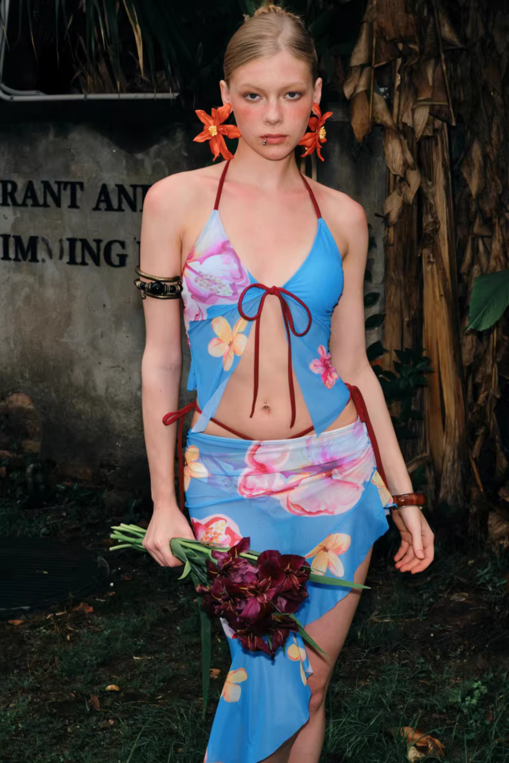 Model wearing a colorful dress with floral patterns against a dark background