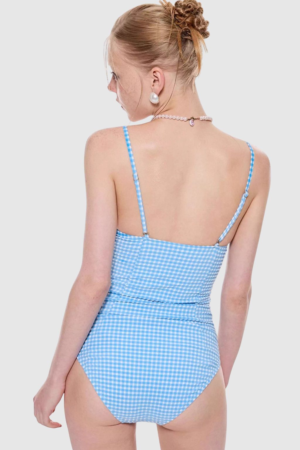 Woman wearing a blue checkered swimsuit on a plain background